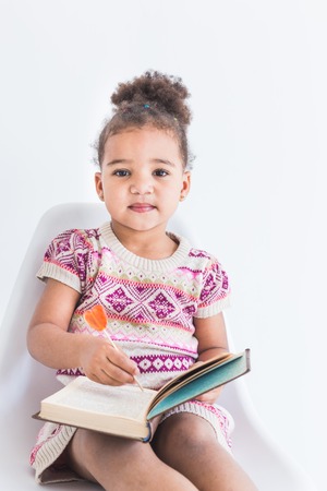 Portrait of a little girl in a colorful dress with a lollipop on a white backgroundの写真素材