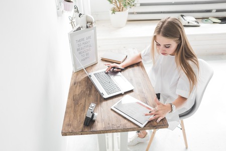 Young business woman working at home behind a laptop and tablet. Creative Scandinavian style...