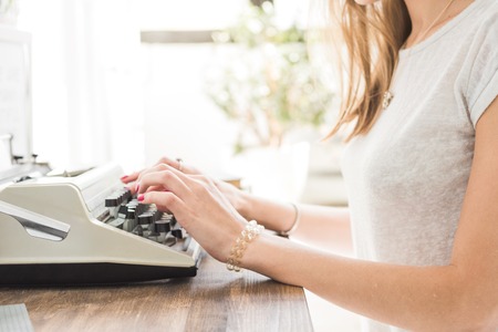Young business woman working at home and typing on a typewriter. Creative Scandinavian style workspaceの写真素材