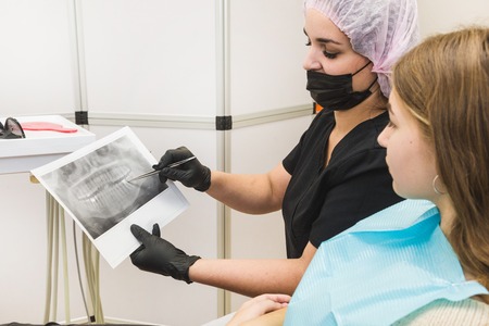 Dental clinic. Reception, examination of the patient. Teeth care. Female dentist in dental office talking with girl patient.の写真素材