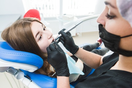 Dental clinic. Reception, examination of the patient. Teeth care. Dentist curing a girl patientの写真素材