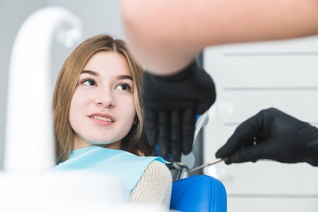 Dental clinic. Reception, examination of the patient. Teeth care. Female dentist in dental office talking with girl patient.の写真素材