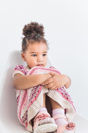 Portrait of a little girl in a colorful dress on a white backgroundの写真素材