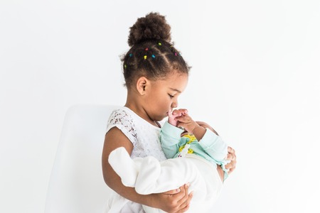 Little girl holding her sister in her arms on white backgroundの写真素材