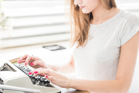 Young business woman working at home and typing on a typewriter. Creative Scandinavian style workspaceの写真素材