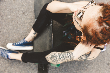 young girl with tattoo and dreadlocks sitting in the parkの写真素材
