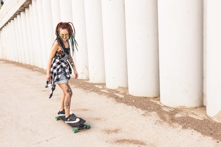 young girl with tattoo rides on a longboardの写真素材