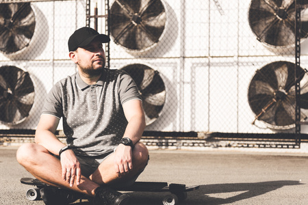 young man in a black cap on a city industrial backgroundの写真素材