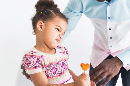 Naughty little girl in a colorful dress and her dad on a white backgroundの写真素材