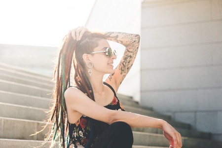 young girl with tattoo and dreadlocks sitting on the stepsの写真素材