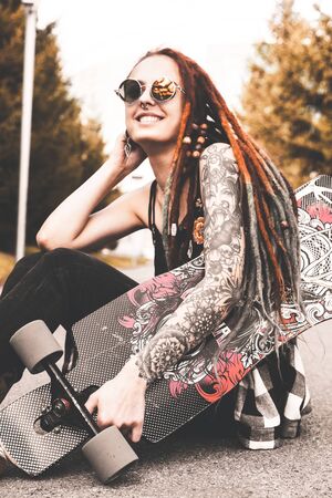 UFA, RUSSIA - September 12, 2018 Editorial photo of young girl with tattoo and dreadlocks sitting in the parkのeditorial素材