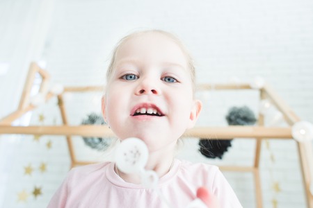 Cute little girl plays with soap bubbles.の写真素材