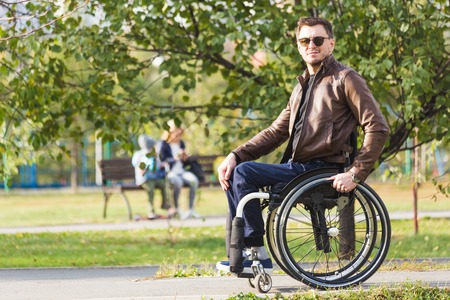 A young man in a wheelchair rides along the park road.の写真素材