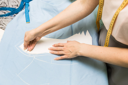 Sewing workshop. Seamstress at work. Marking and cutting fabric.