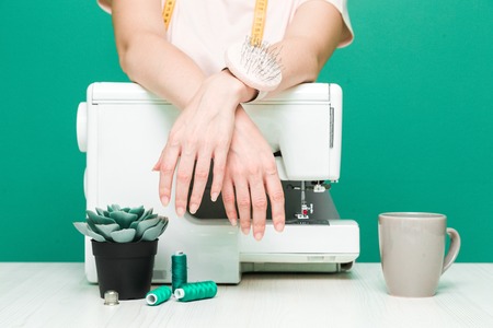 Sewing workshop. Close-up of seamstress hands on a colored background.