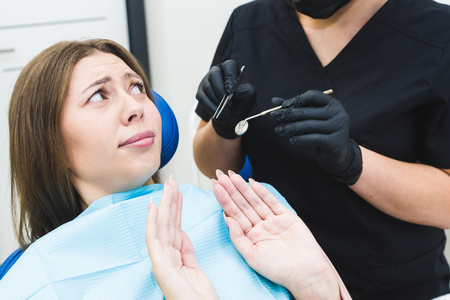 Dental clinic. Reception, examination of the patient. Teeth care. Young woman feels fear at the dentistの写真素材