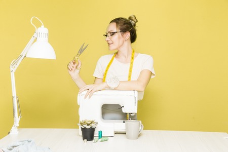 Sewing workshop. Seamstress at work. Portrait of a young dressmaker with scissors on a colored...