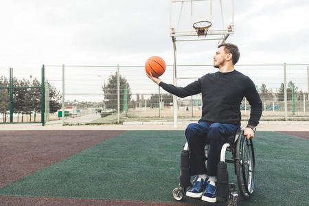 Young man in a wheelchair playing basketball.の写真素材