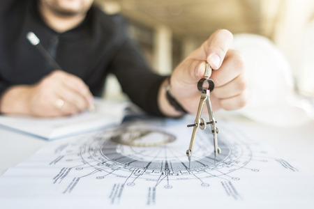 architect builder works at the table with drawings. Helmet, drawings, compasses in the workplaceの写真素材