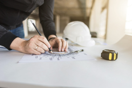 architect builder works at the table with drawings. Helmet, drawings, compasses in the workplace