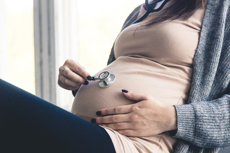 pregnancy, gynecology, medicine, health care and people concept - stethoscope listening to pregnant...