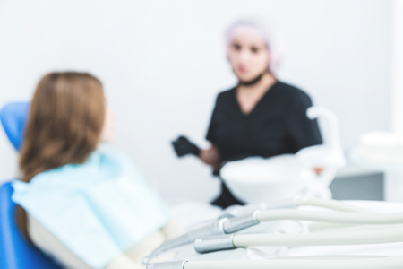 Dental clinic. Reception, examination of the patient. Teeth care. Female dentist in dental office talking with girl patient.の写真素材