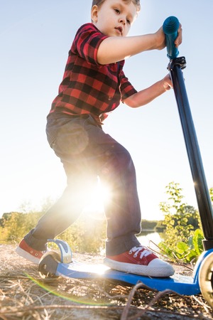 Young happy family with childrens having fun in nature. Boy riding a scooterの写真素材