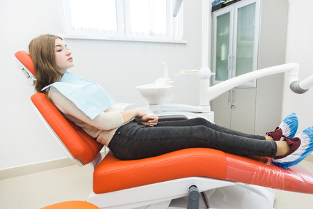 Dental clinic. Reception, examination of the patient. Teeth care. The girl is sitting in the dental chair ready to examine the teethの写真素材
