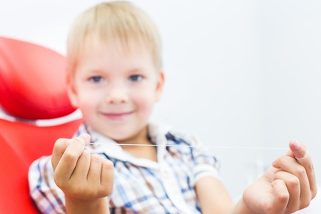 Dental clinic. Reception, examination of the patient. Teeth care. A little boy with dental floss sits in a dental chair. Oral hygiene conceptの写真素材