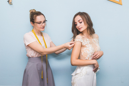 Sewing workshop. Seamstress at work. Seamstress takes measurements of a wedding dressの写真素材