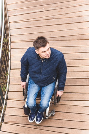 Man in a wheelchair use a wheelchair ramp.