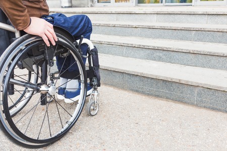 Man in wheelchair in front of stairs.の写真素材