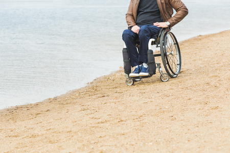 Young man sitting in a wheelchair by the lake.の写真素材