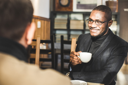 Multicultural african and caucasian businessmen negotiate in a cafe.の写真素材
