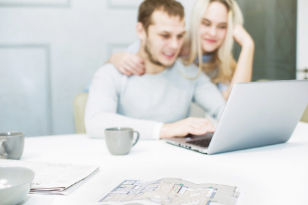 Lovely young couple, using a laptop and choosing a new apartment.