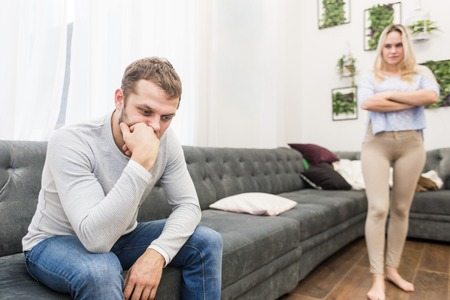 Unhappy young couple quarreling in the living room.