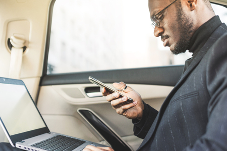 Man in a business suit write on laptop in the salon of an expensive car with leather interior.の写真素材