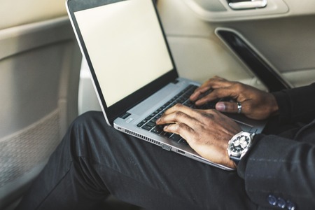 Man in a business suit write on laptop in the salon of an expensive car with leather interior.