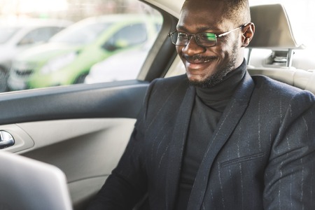 Man in a business suit write on laptop in the salon of an expensive car with leather interior.