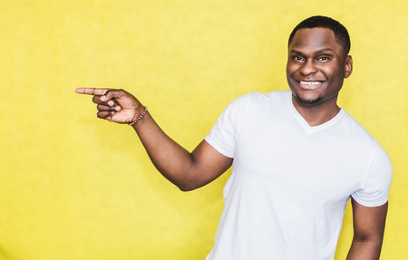 Handsome African American man indicates with forefinger at blank copy space.の写真素材