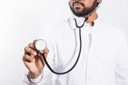 Doctor in a white coat holding a stethoscope in his hand.
