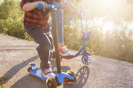 Young happy family with childrens having fun in nature. The boy with his mother rides a scooterの写真素材