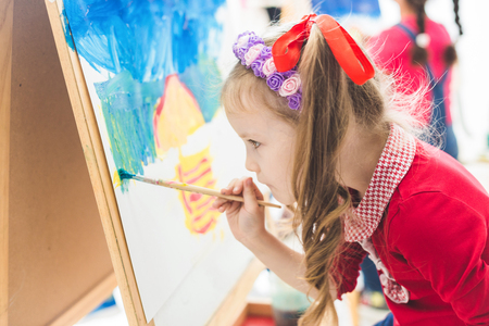 little girl with a teacher in group of preschool student sat the drawing a picture. Painting on maelbert, palette and paints. Back to school and Education concept.の写真素材