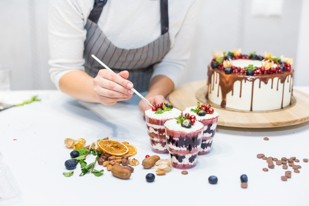 Decoration of the finished dessert. Pastry chef sprinkles confectionery with yellow powder. The...