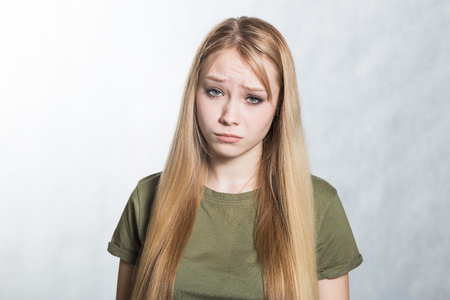 Portrait of a young beautiful sad woman on a gray background.の写真素材