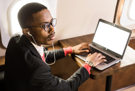 Attractive and successful African American businessman with glasses working on a laptop while...