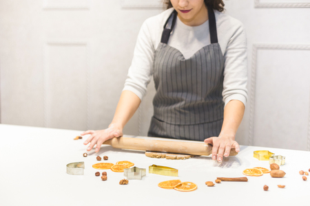 Young pretty woman prepares the dough and bakes gingerbread and cookies in the kitchen. Merry Christmas and Happy New Year.の写真素材