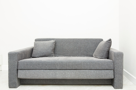 Classic modern gray sofa with pillows in the bright interior of the apartmentの写真素材