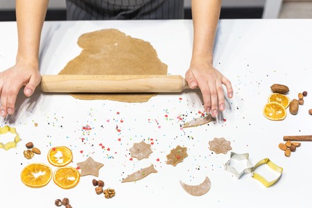 Young pretty woman prepares the dough and bakes gingerbread and cookies in the kitchen. Merry...