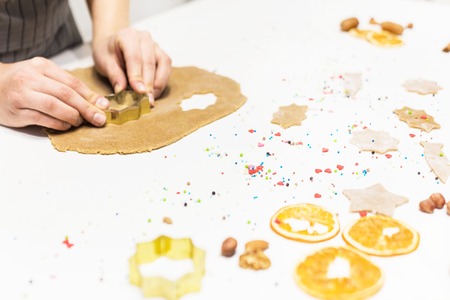 Young pretty woman prepares the dough and bakes gingerbread and cookies in the kitchen. She makes a...